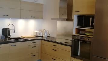 A modern kitchen with a stainless steel sink, a toaster, a kettle, and a microwave.