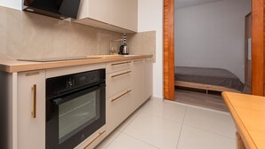 Eine kleine Küche mit eingebautem Ofen, einer Kaffeemaschine und einer Holz Arbeitsplatte.