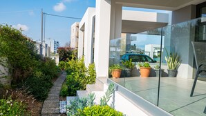 Ein modernes Wohngebäude mit Glasbalkon, Blumentöpfen und freiem Blick auf die Straße.