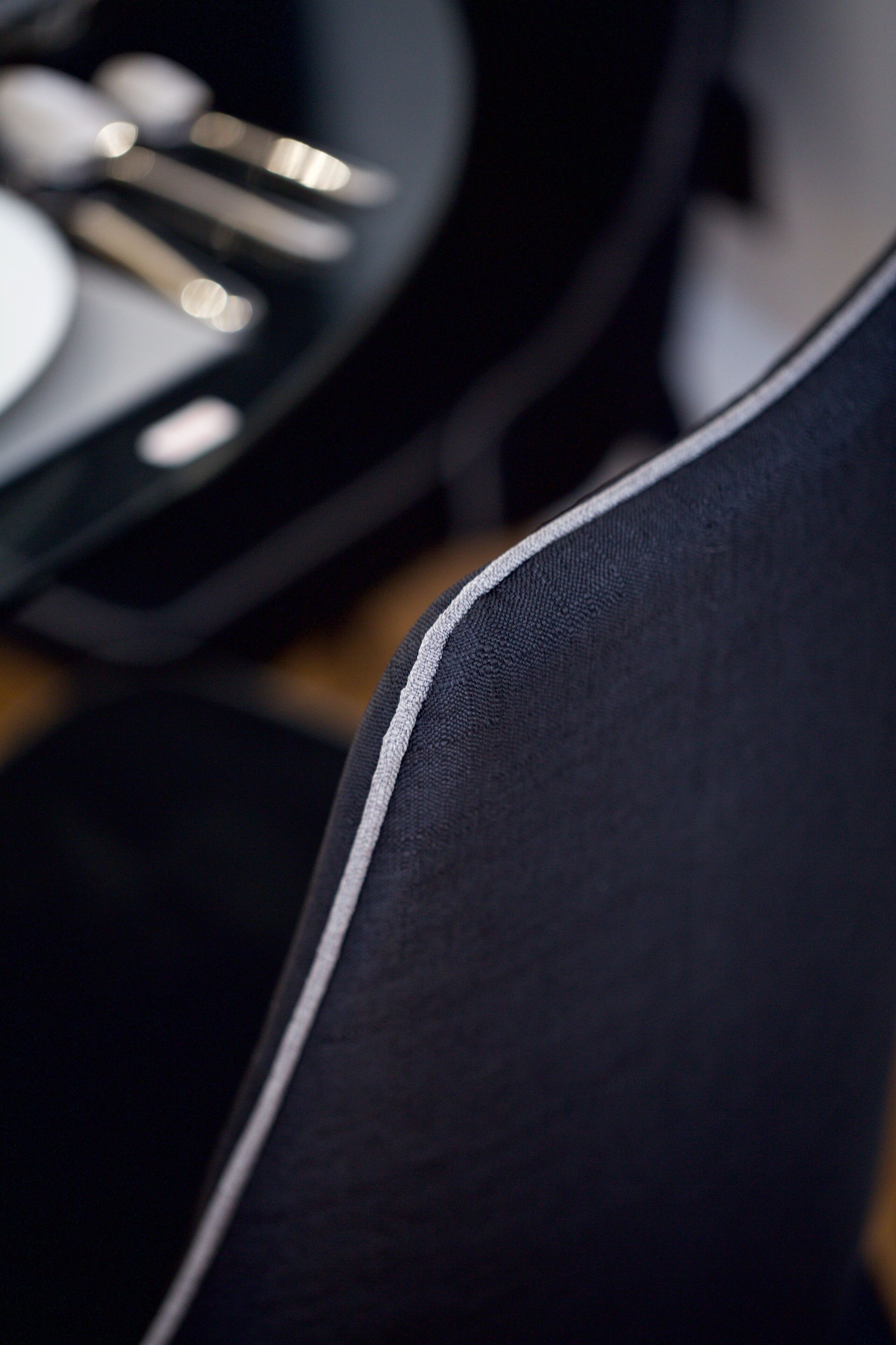 A close-up of a chair with a grey and black fabric and a white zipper.