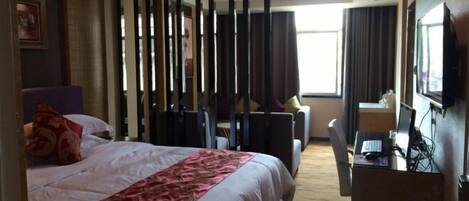 A hotel room with a bed, a desk with a computer, a chair, and a TV.