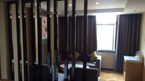 Een moderne hotelkamer met een zithoek, een klein tafeltje en een decoratieve wand.