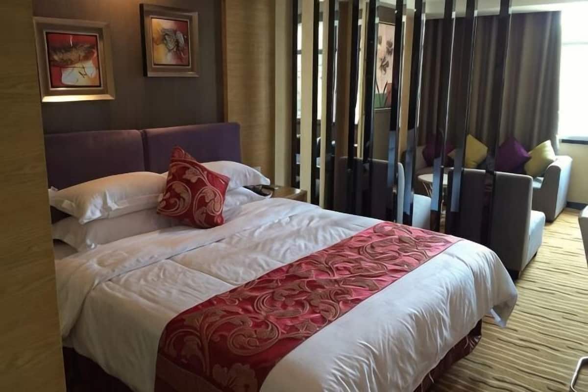 A hotel room with a large bed, a sofa, and a view of the outdoors.