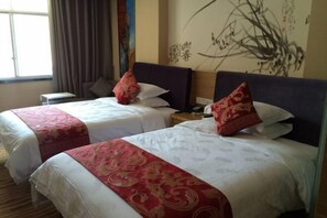 Habitación de hotel con dos camas, cada una con una colcha roja y blanca, una mesita de noche y una pared con arte caligráfico.