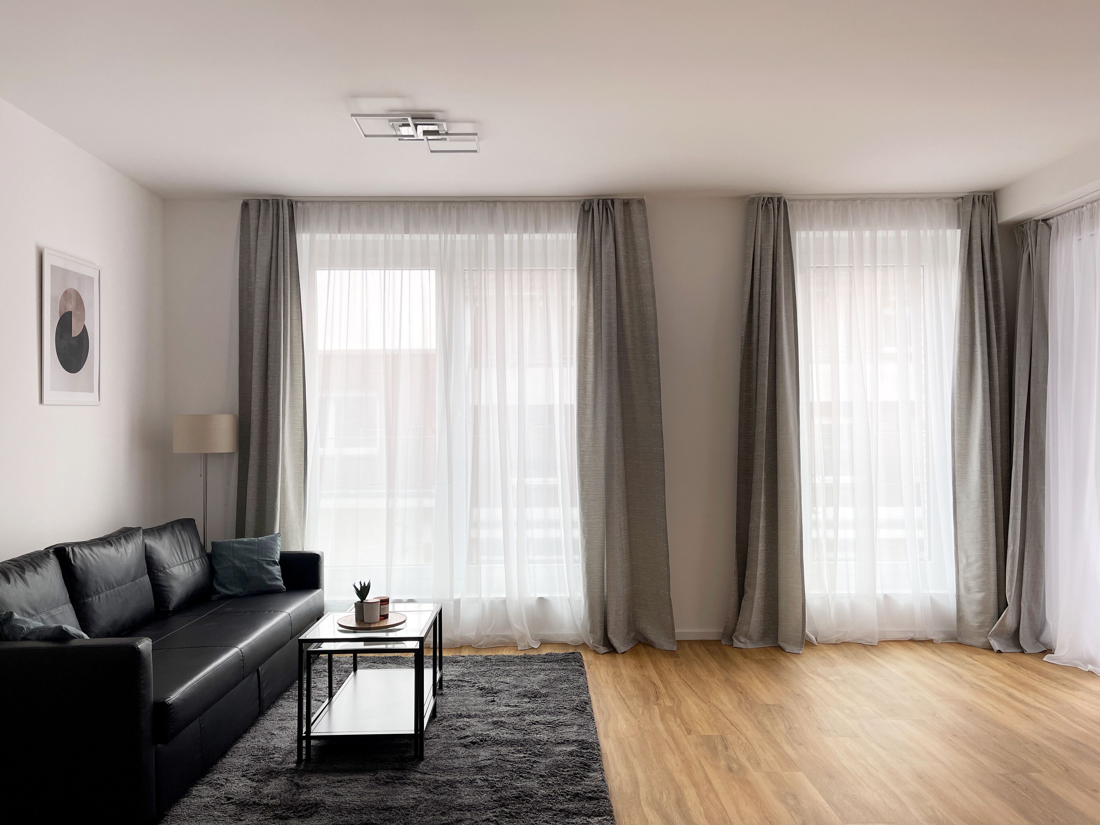 Ein modernes Wohnzimmer mit einer schwarzen Ledersofa, einem kleinen Couchtisch und einem Teppich.