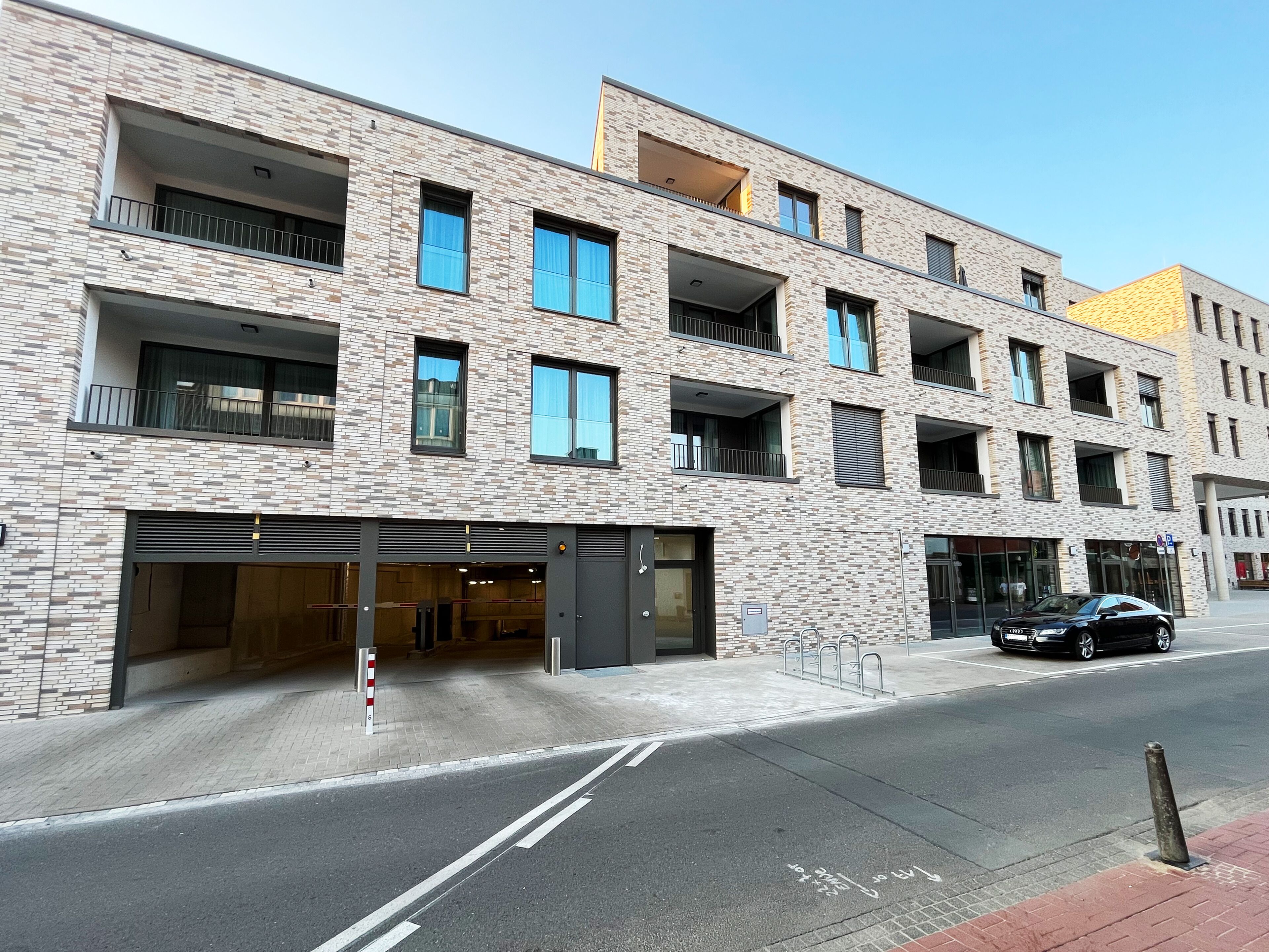 A modern multi-story building with a brick facade, large windows, and a ground-level entrance.