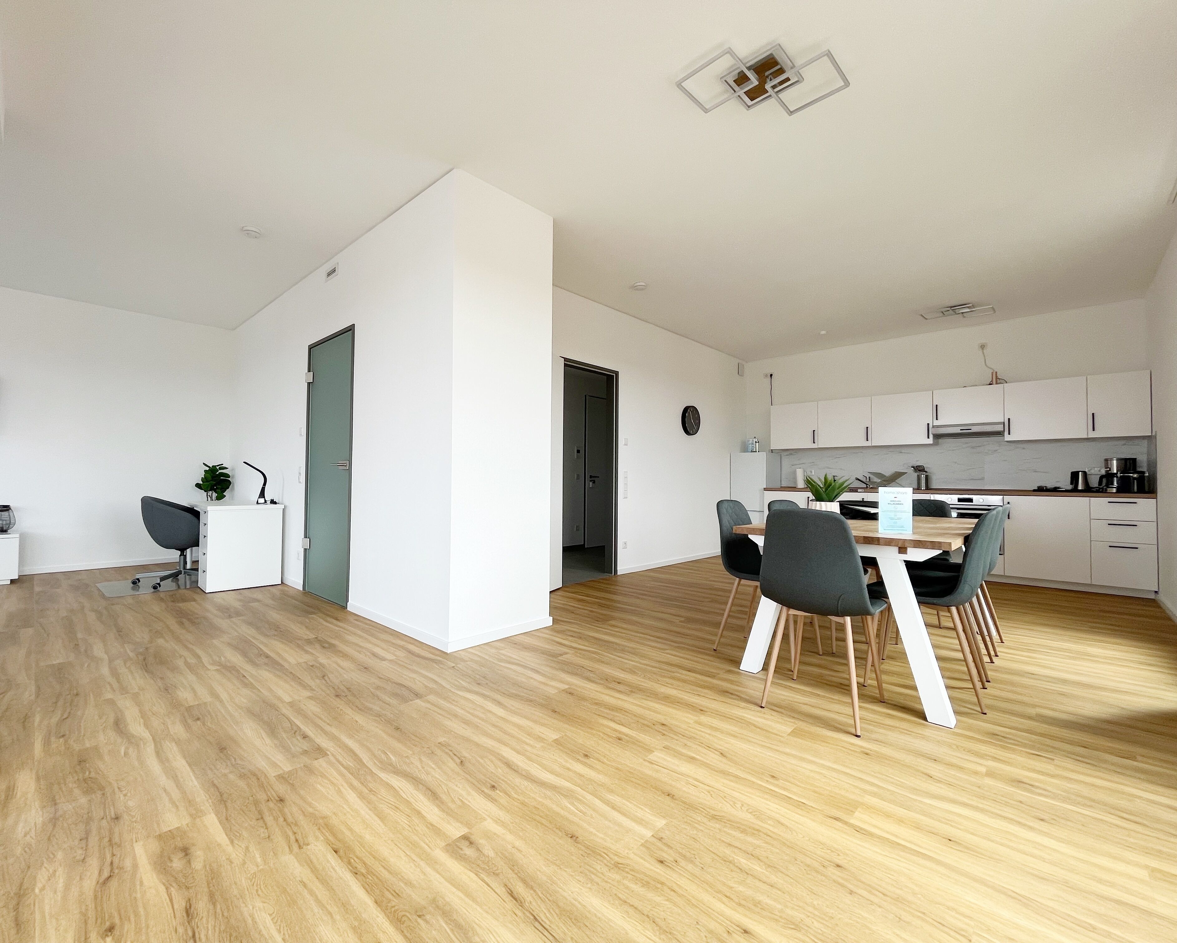 Een modern appartement met een eethoek, keuken en een klein kantoor.