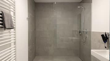 A modern bathroom with a glass-enclosed shower, a white sink, and a towel rack.