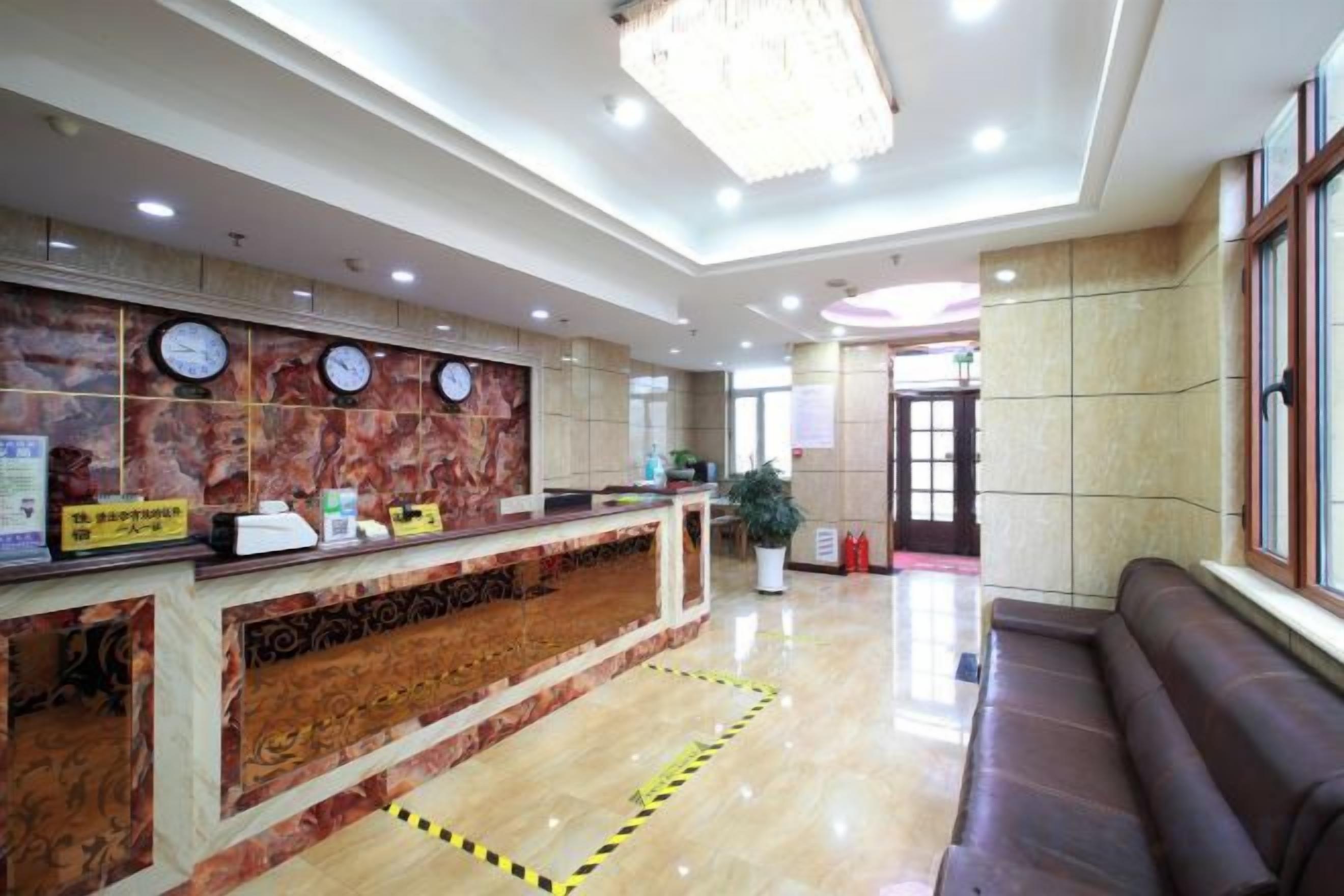 A hotel reception area with a marble reception desk, clocks, a sofa, and a large window.