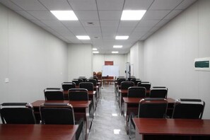 A conference room with rows of tables and chairs, a whiteboard, and a projector screen. - Huihai Hotel (Xinbin)