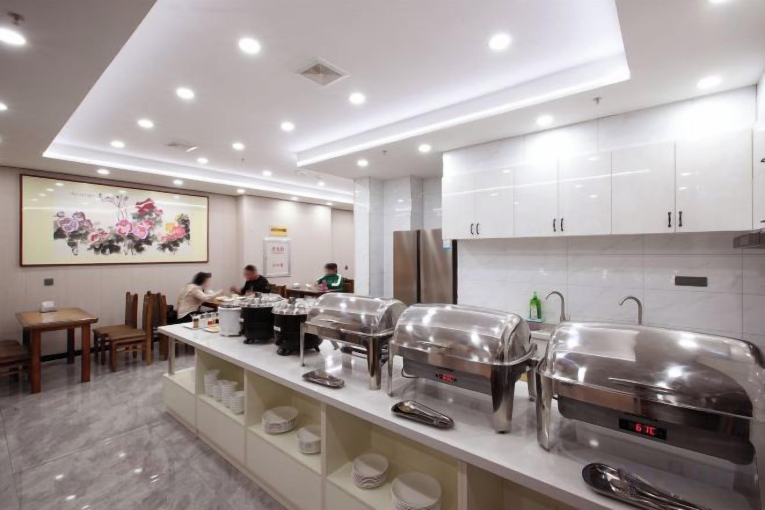 Una cocina moderna con electrodomésticos de acero inoxidable, un montaje tipo buffet y un comedor con sillas y mesas.