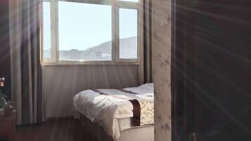 Een slaapkamer met een bed, een raam en een deur.