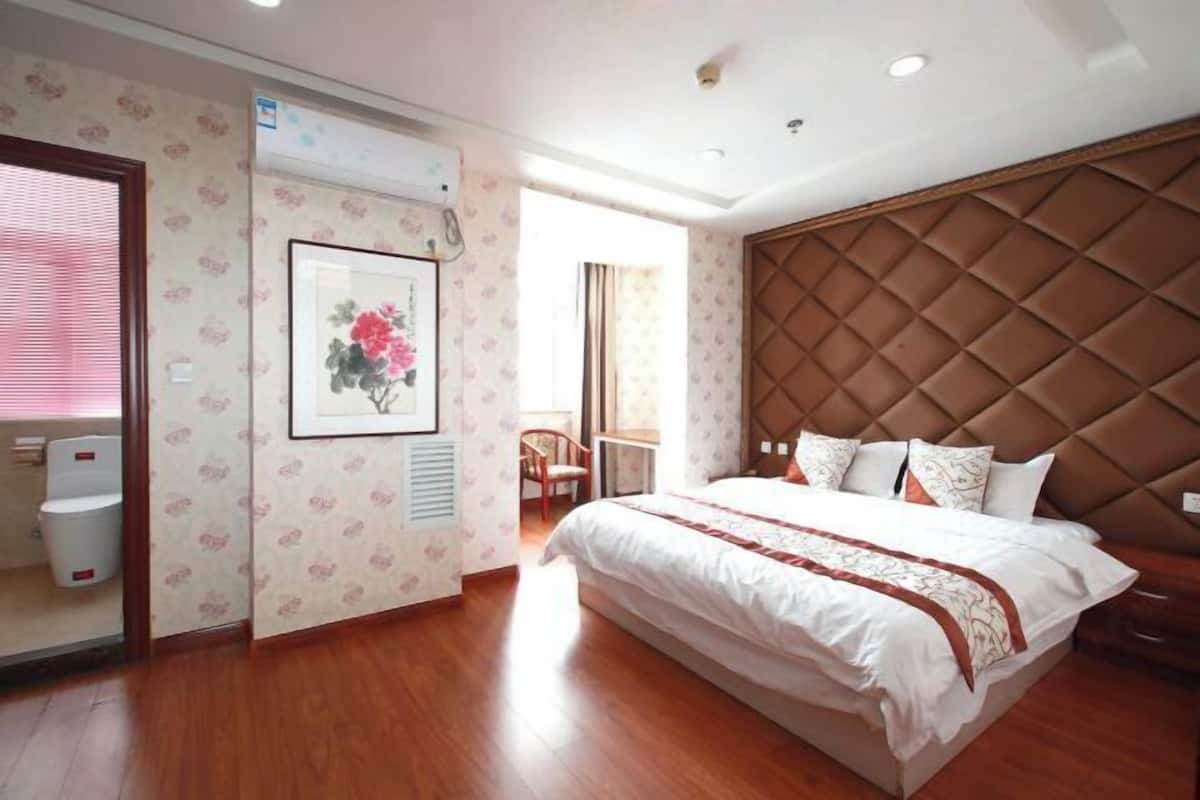 A bedroom with a large bed, a wooden headboard, and a framed picture on the wall.