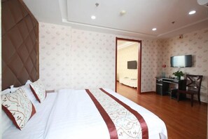 A hotel room with a large bed, a desk, and a television. - Huihai Hotel (Xinbin)