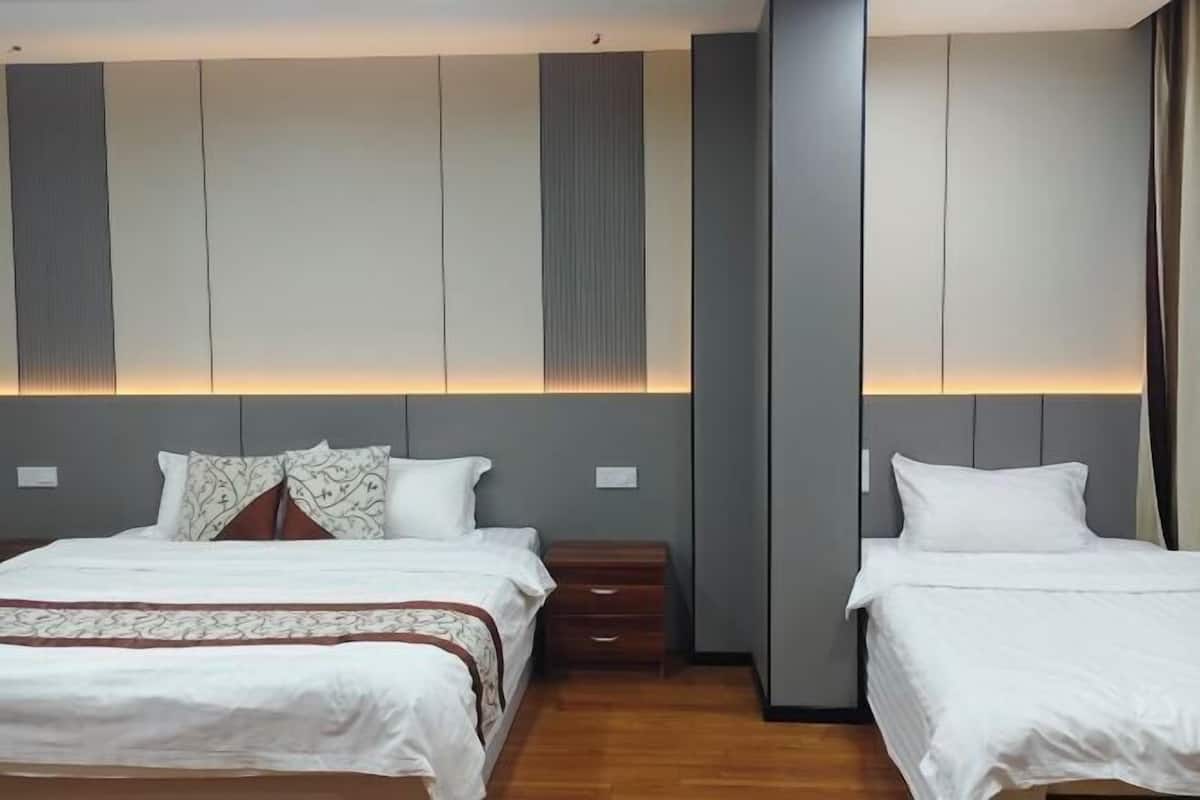 A hotel room with two beds, a nightstand, and a wall panel design.