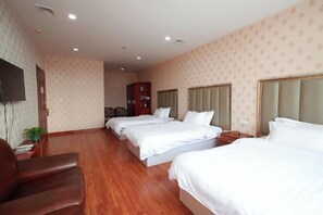 A hotel room with three beds, a TV, a wooden floor, and a red cabinet. - Huihai Hotel (Xinbin)