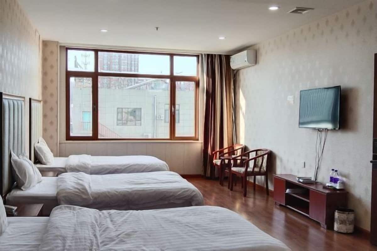 A hotel room with two beds, a TV, and a window with curtains.