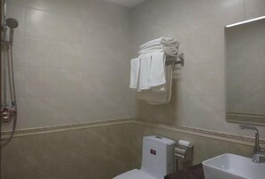 A bathroom with a toilet, sink, and towel rack. - Huihai Hotel (Xinbin)