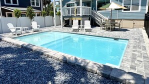 Una casa de dos pisos con piscina, barandillas blancas y un patio cubierto.