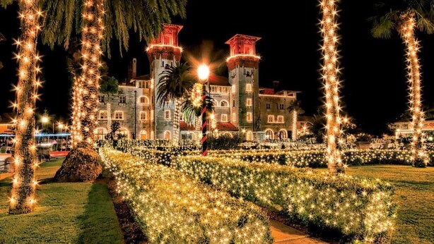 Un edificio grande con dos torres, rodeado de un jardín con luces en forma de estrella.