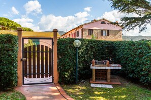 A gated entrance with a brick pathway leading to a building with a pink facade and stone accents.