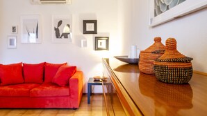 Ein Wohnzimmer mit einem roten Sofa, einem kleinen Tisch und Dekoration auf einem Holztisch.