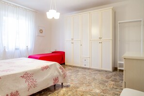 A bedroom with a bed, a wardrobe, and a nightstand.