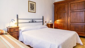 Ein Schlafzimmer mit Bett, Nachttischen, einem Kleiderschrank und einem gerahmten Bild an der Wand.