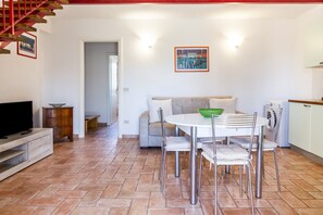 Un espace repas comprenant une table ronde, des chaises, un téléviseur et un escalier.