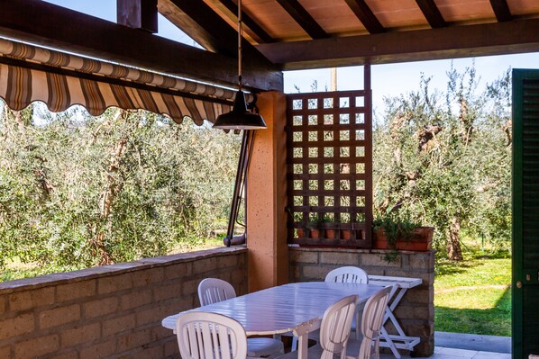 Un patio al aire libre con una mesa y sillas, una lámpara colgante y una cerca de listones de madera.
