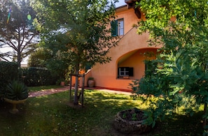 A house with a garden, a pathway, and a large tree. - Holiday Home "Palmiro" with Shared Garden & Wi-Fi (Castiglione della pescaia)