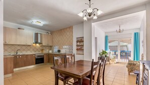A modern kitchen with wooden cabinets, a dining table, and chairs. There is a built-in oven, microwave, and sink. The room has a tiled floor and a chandelier. - Holiday Home "Adriana" with Private Pool, Terrace, and Wi-Fi (Murchas)