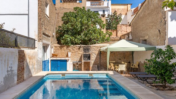 A swimming pool with a tiled edge, a stone wall, and a covered seating area with tables and chairs. - Holiday Home "Adriana" with Private Pool, Terrace, and Wi-Fi (Murchas)