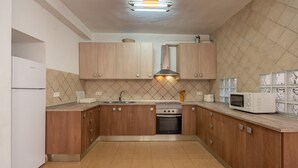 A modern kitchen with wooden cabinets, a built-in oven, a microwave, and a sink. - Holiday Home "Adriana" with Private Pool, Terrace, and Wi-Fi (Murchas)