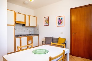 Una cocina compacta con armarios de madera, una encimera blanca y una mesa de comedor con sillas.