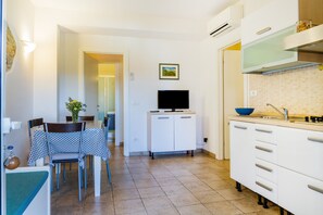 A compact kitchen with a dining area, a TV, and a sink.