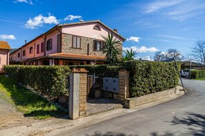 Une villa rose à la façade en pierre, dotée d’une entrée sécurisée et surplombant un ciel d’un bleu limpide.