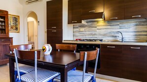 Une cuisine moderne avec des meubles de couleur bois foncé, un pare-feu en acier inoxydable et un coin repas comprenant une table et des chaises en bois.