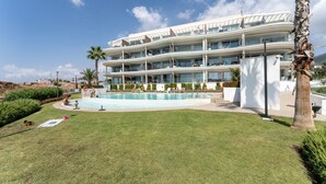 Un hôtel à plusieurs étages doté d’une piscine, de palmiers et surplombant un ciel dégagé.
