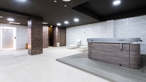 Un espace spa moderne doté d’un jacuzzi, de sièges et d’un mur carrelé.