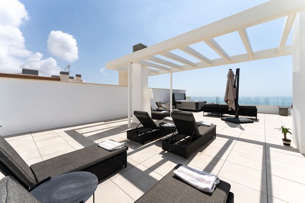 Une terrasse sur le toit avec des sièges extérieurs, une pergola et une vue sur la ville.