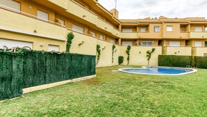 A courtyard with a swimming pool, green hedges, and a building with balconies and windows. - Apartment 'Montgo' with Mountain View, Wi-Fi and Air Conditioning (L'Escala)