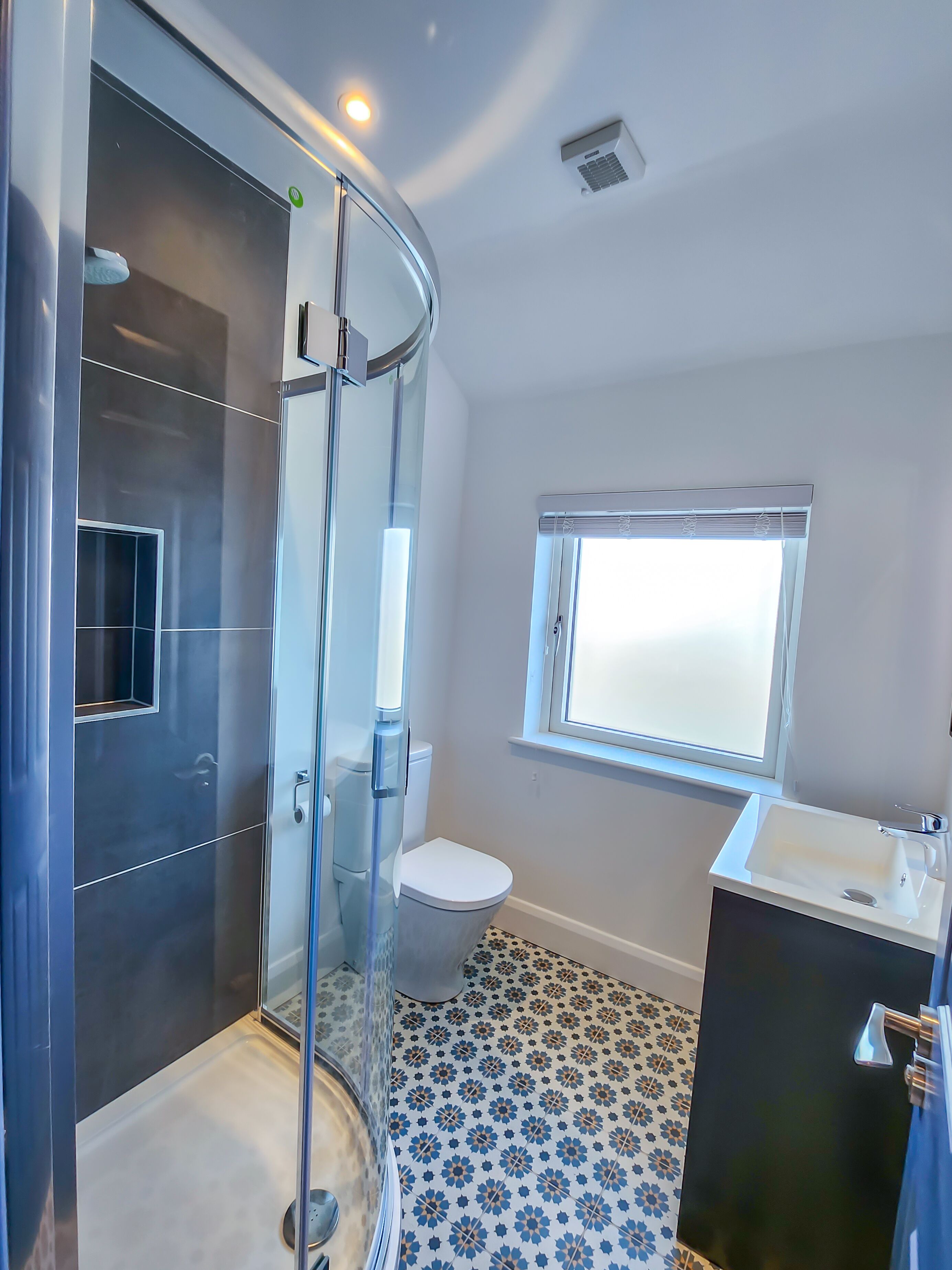 A modern bathroom with a glass shower enclosure, a toilet, and a sink.