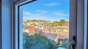 Une fenêtre donnant sur un quartier résidentiel, avec vue sur des maisons et des espaces verts.