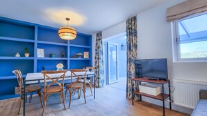 Un salon moderne avec un mur d’accent bleu, des meubles en bois, un téléviseur et une grande fenêtre.