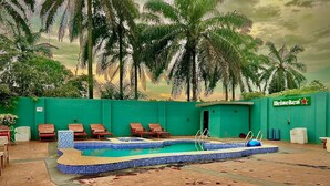Zona de piscina con sillones de descanso y un cartel de Heineken.