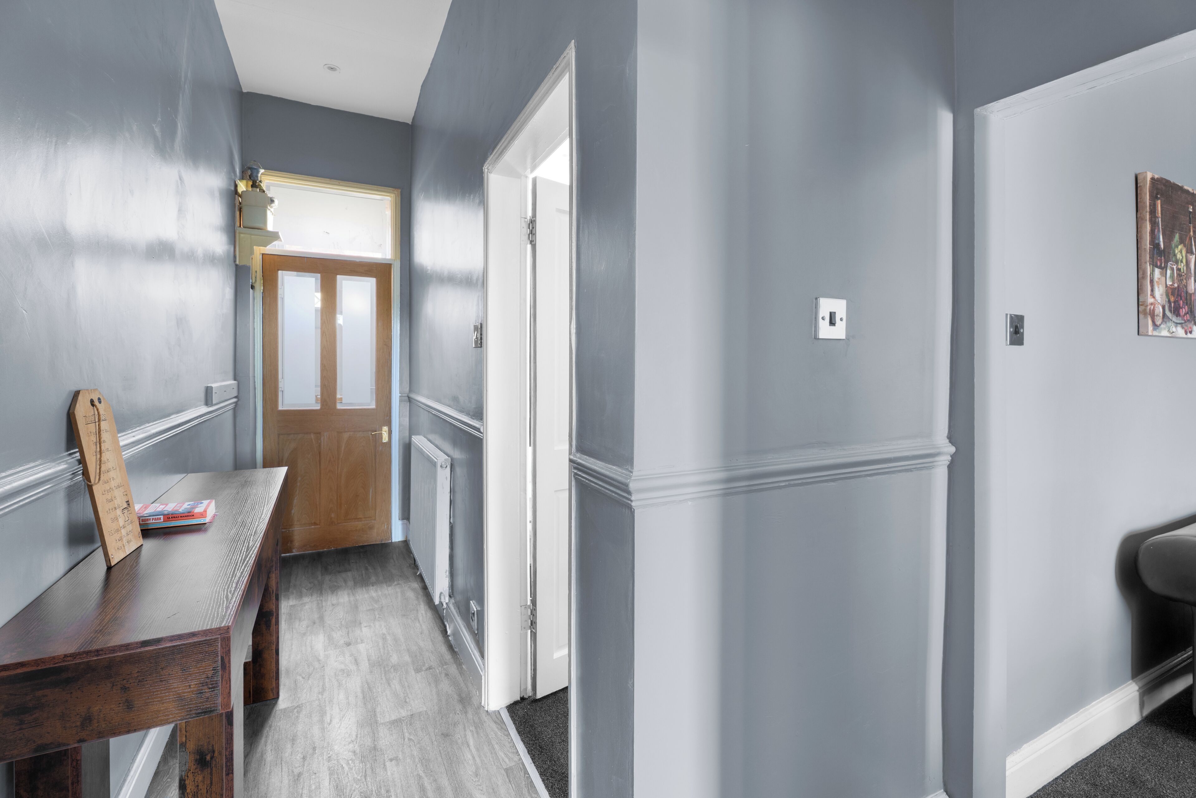 A hallway with a wooden table, a door, and a radiator.