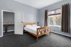 A bedroom with a bed, a wardrobe, a window with curtains, and a view of the outside.