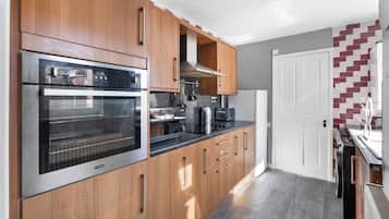 A modern kitchen with wooden cabinets, stainless steel appliances, and a tiled backsplash.