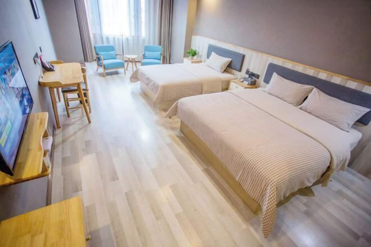 Hotellihuone, jossa on kaksi sänkyä, työpöytä, tuoli ja televisio.